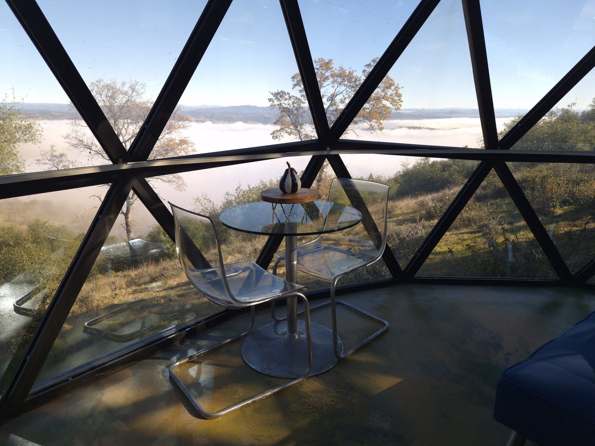 Glass table and chairs above a valley of fog