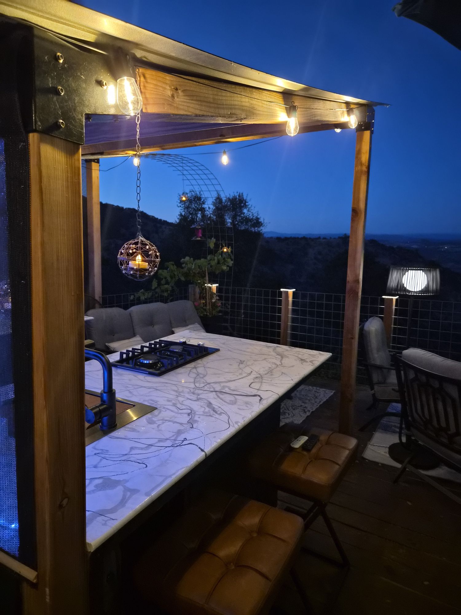 Marble bar and cooktop under string lights at blue hour